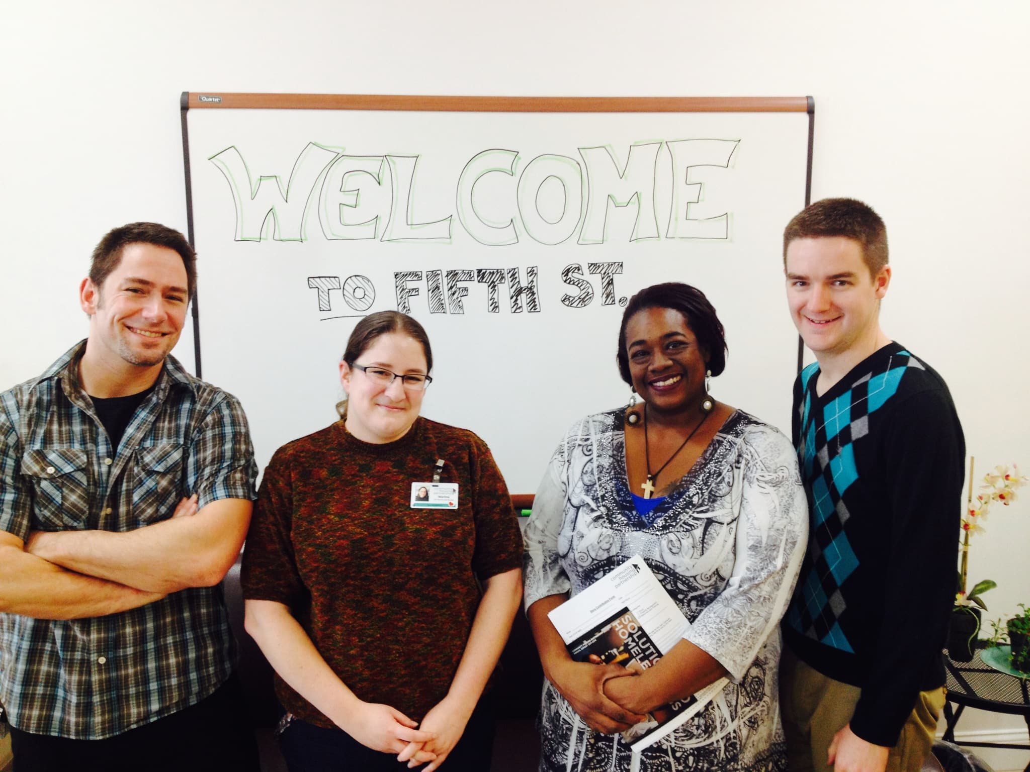 smiling people in front of welcome to fifth st sign